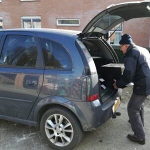 Vrijwilliger laadt de cassettes met maaltijden in zijn auto en gaat deze tafeltje dekje maatlijden persoonlijk afleveren